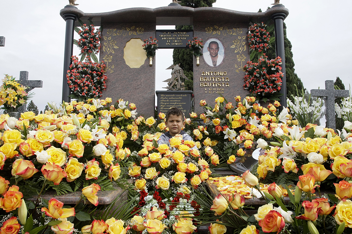 Murcia, 01.11.2008.-  Un niño posa en la tamba de su padre, rodeado por las flores que ha llevado la familia con motivo del día de todos los santos, en el cementerio de Murcia.  Pilar Morales.